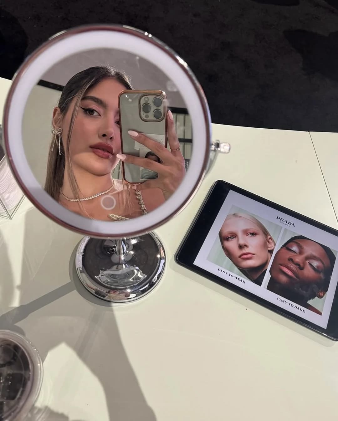 Yasaman taking a mirror selfie at a Prada Beauty makeup station