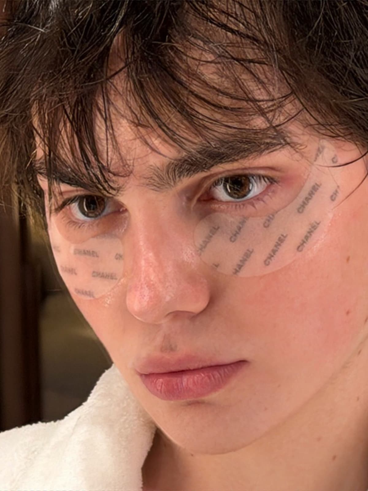 Anton in a white robe with under-eye patches and dewy skin.